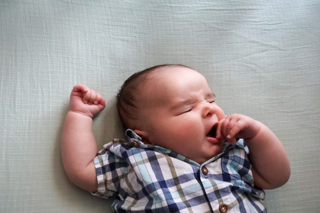 Baby yawning with hand over mouth