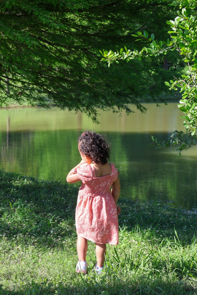 Girl in pink dress looking at pond