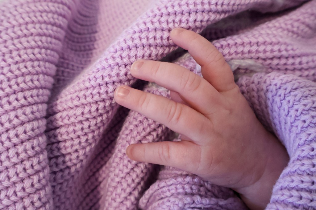 Newborn hands against pink sweater