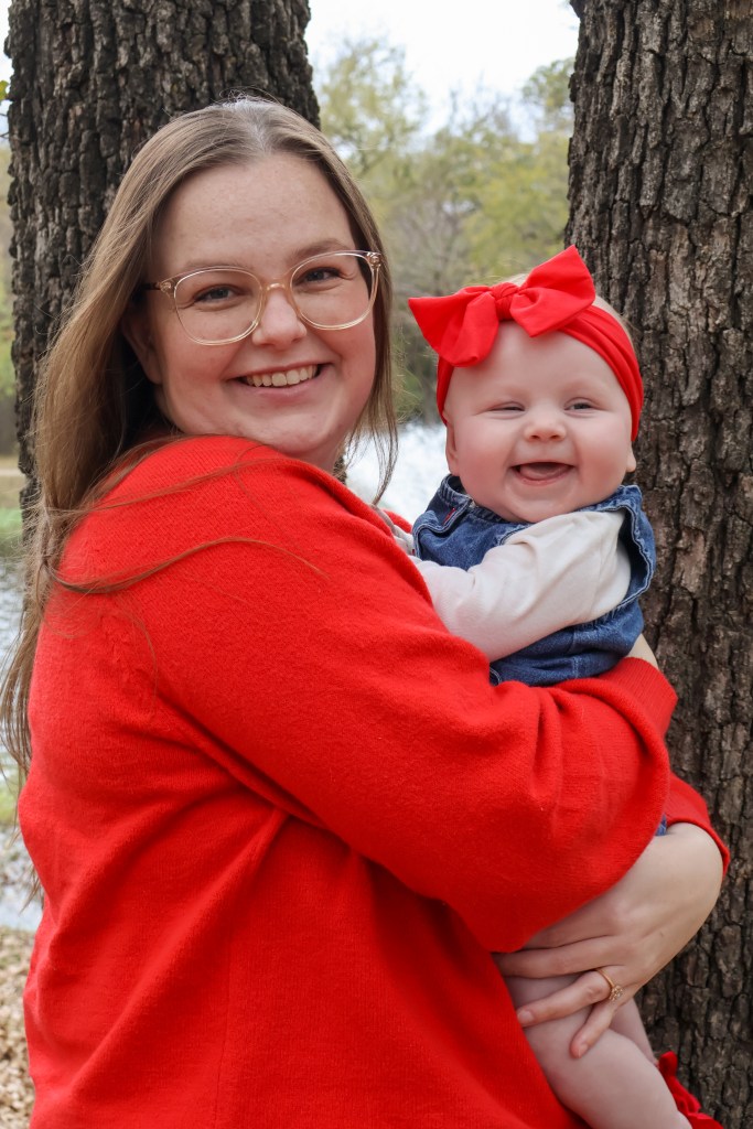 Mother and baby daughter smiling in matching red outfits